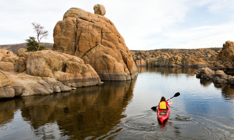 Woman Kayaks the shores of Watson Lake in Prescott Arizona